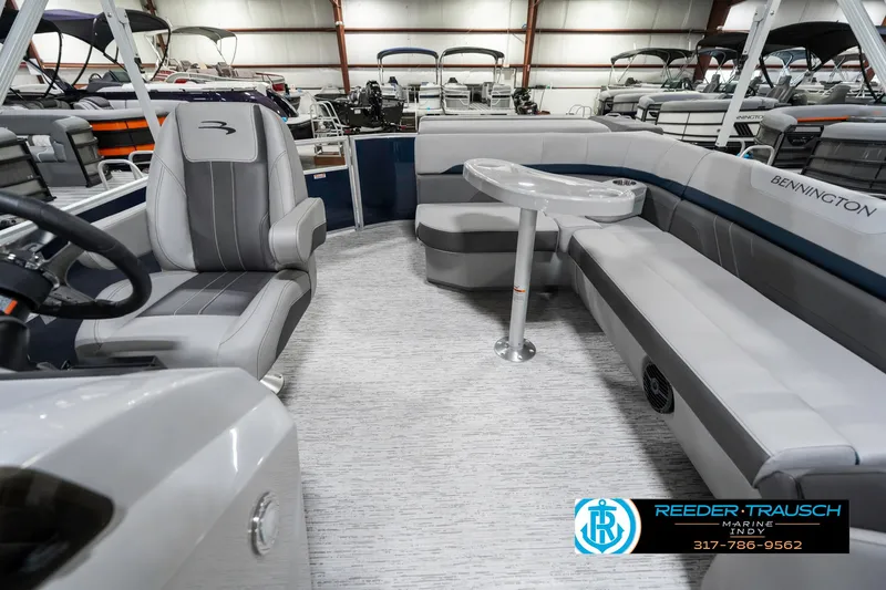 Slide: The Image of 2025 Bennington 22 SXL boat interior with gray seating and table in a showroom. - 17