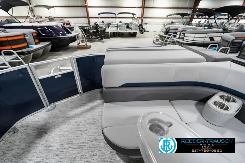 Slide: The Image of 2025 Bennington 22 SXL pontoon boat interior with plush seating and cup holders in showroom. - 18