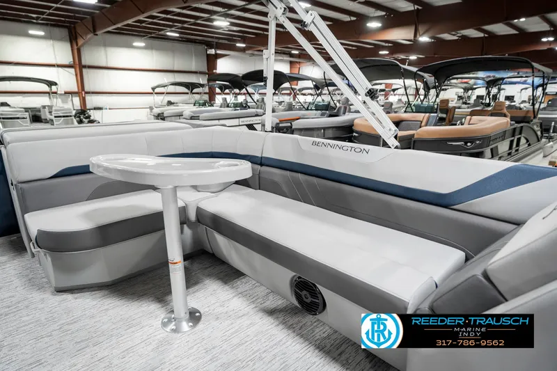 Slide: The Image of 2025 Bennington 22 SXL pontoon boat interior with seating and table in showroom. - 26