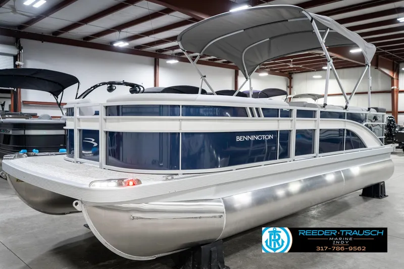 Slide: The Image of 2025 Bennington 22 SXL pontoon boat in showroom, featuring sleek design and canopy. - 3