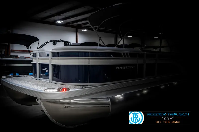 Slide: The Image of 2025 Bennington 22 SXL pontoon boat in showroom, featuring sleek design and modern lighting. - 4