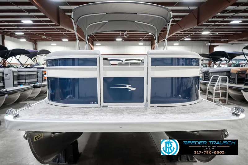 Slide: The Image of 2025 Bennington 22 SXL pontoon boat in showroom, featuring sleek blue and white design. - 5