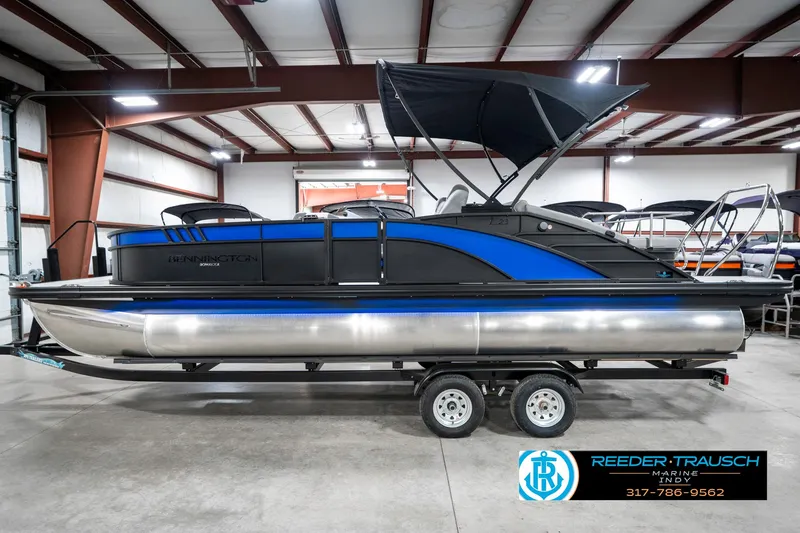 Slide: The Image of 2025 Bennington 23 LTSB pontoon boat in showroom, featuring sleek design and blue accents. - 11