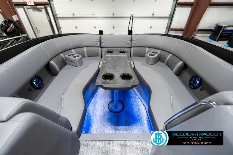 Slide: The Image of 2025 Bennington 23 LTSB boat interior with gray seating, blue lighting, and cup holders. - 21