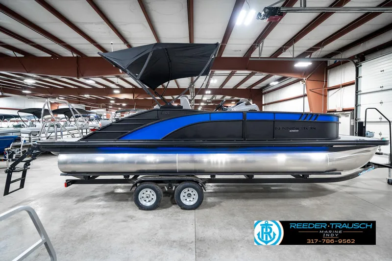 Slide: The Image of 2025 Bennington 23 LTSB pontoon boat in showroom, featuring sleek blue and black design. - 7