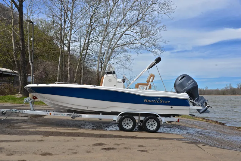 Slide: The Image of 2023 NauticStar 211 Hybrid boat on trailer by a lakeside ramp. - 11
