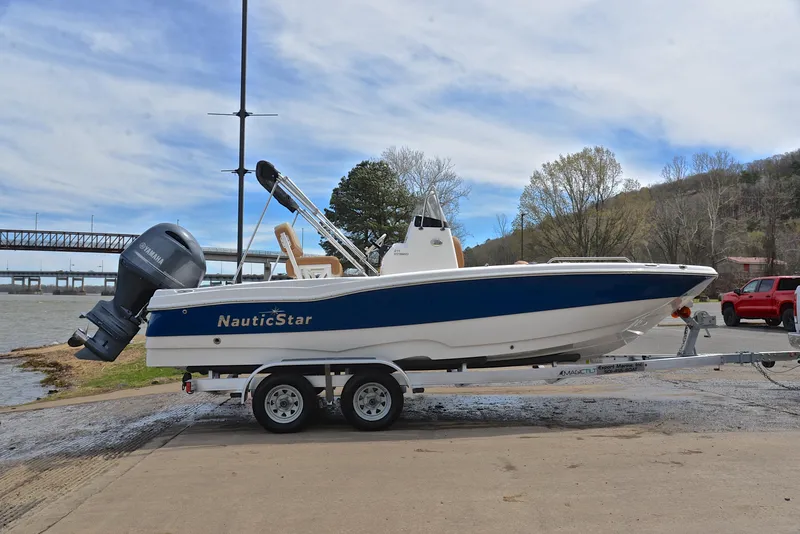 Slide: The Image of 2023 NauticStar 211 Hybrid boat on trailer by river, ready for launch. - 15