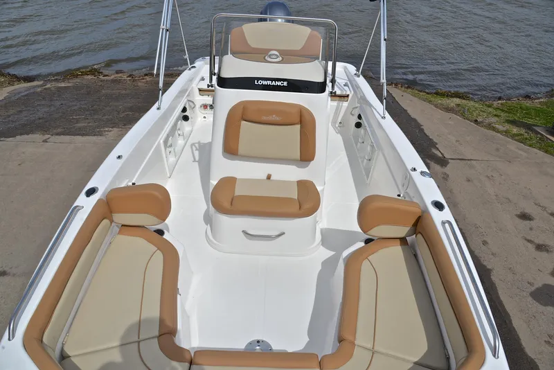 Slide: The Image of 2023 NauticStar 211 Hybrid boat with tan seating, docked by the water. - 21