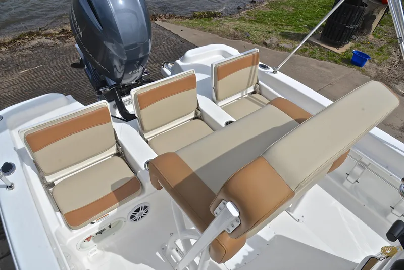 Slide: The Image of 2023 NauticStar 211 Hybrid boat interior with tan and white seating, near water. - 23