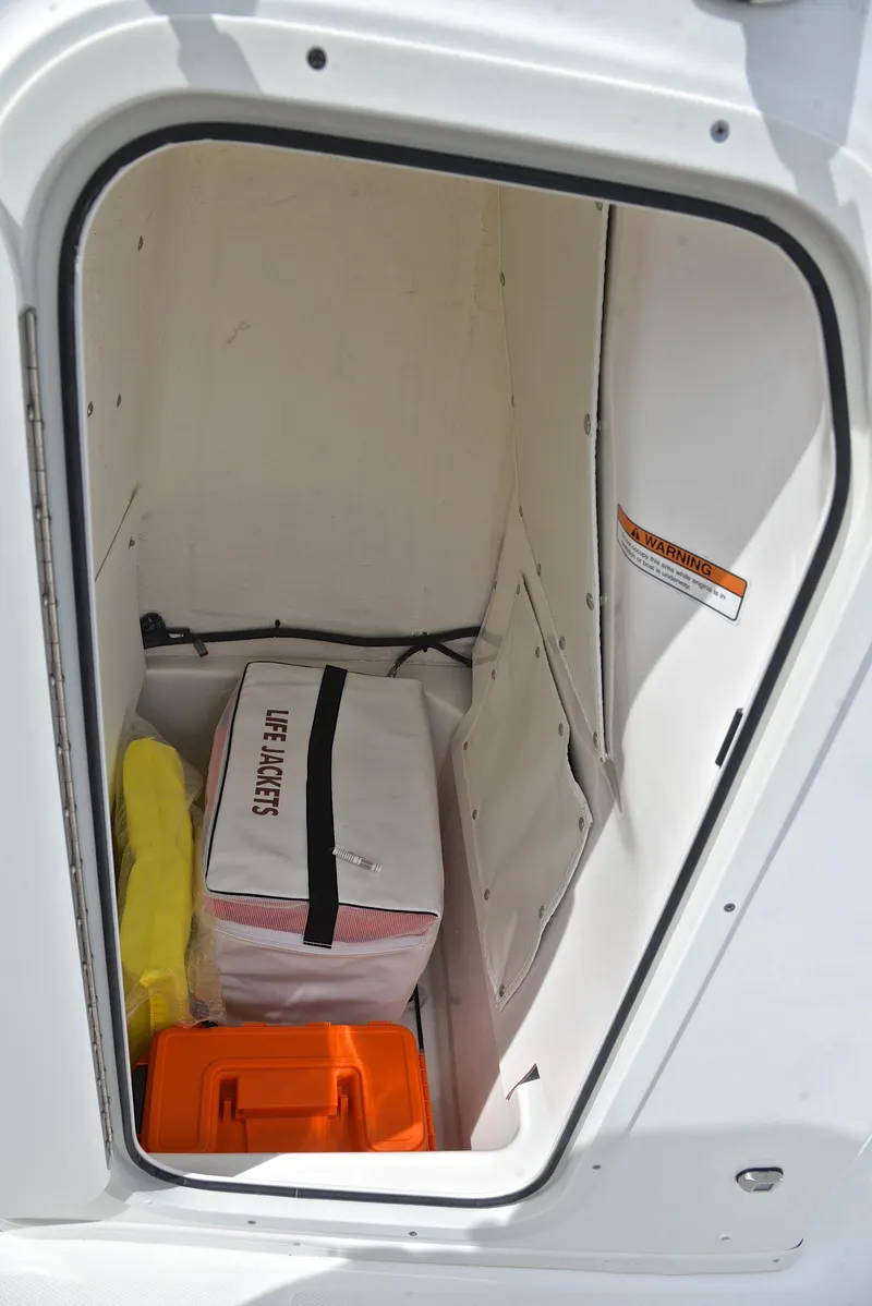 Slide: The Image of Storage compartment in 2023 NauticStar 211 Hybrid boat with life jackets and safety gear. - 26