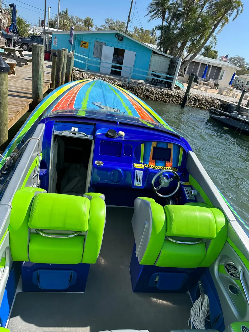 Slide: The Image of 2008 Outerlimits 39 Quattro boat with vibrant green and blue interior docked by waterfront. - 19