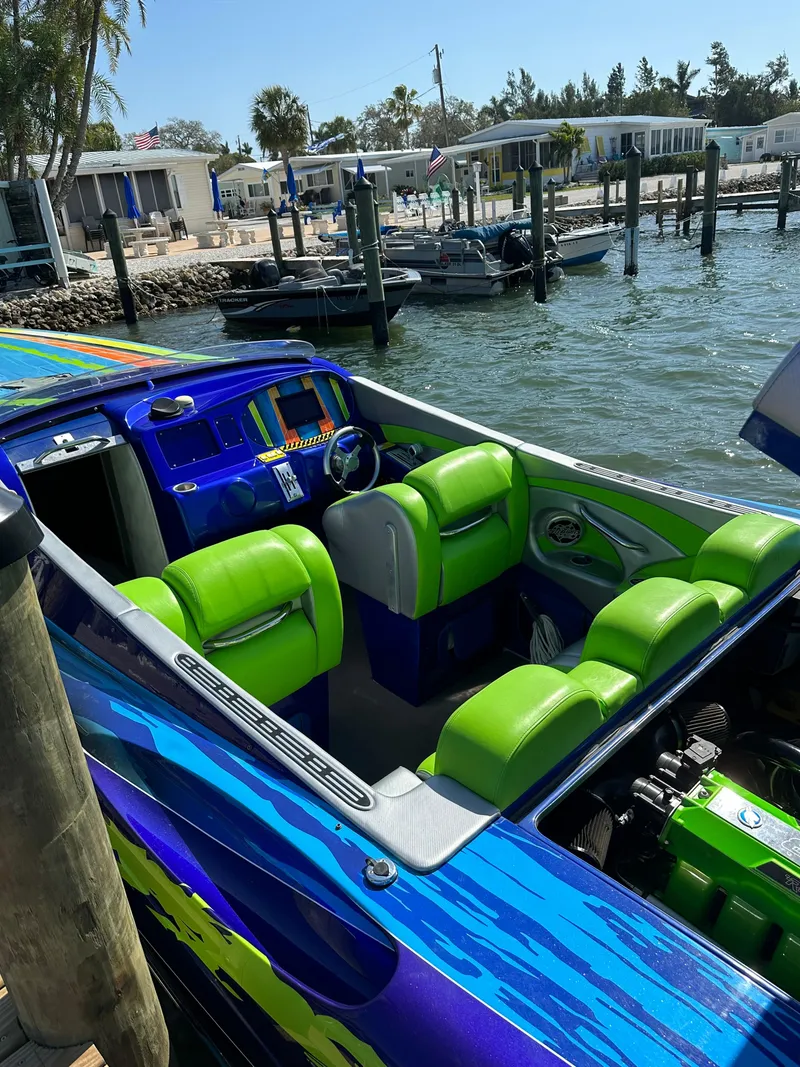Slide: The Image of 2008 Outerlimits 39 Quattro speedboat with vibrant green and blue interior, docked by waterfront. - 22