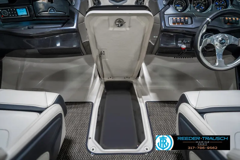 Slide: The Image of Interior of 2013 Monterey 232 SS boat showing storage compartment and dashboard controls. - 28