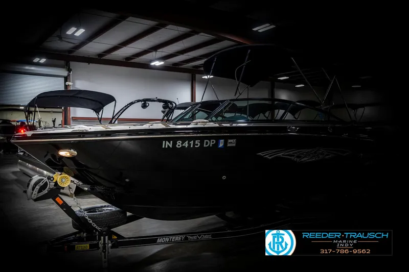Slide: The Image of 2013 Monterey 232 SS boat in a dimly lit indoor setting on a trailer. - 4