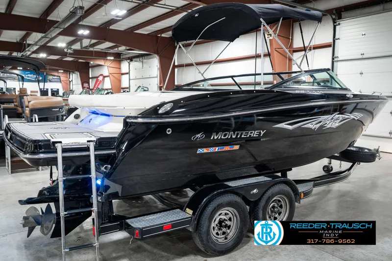 Slide: The Image of 2013 Monterey 232 SS boat in showroom, black exterior, on trailer, with bimini top. - 8