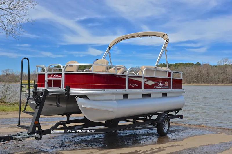 Slide: The Image of 2018 Sun Tracker Bass Buggy 18 DLX pontoon boat on trailer by a lake. - 10