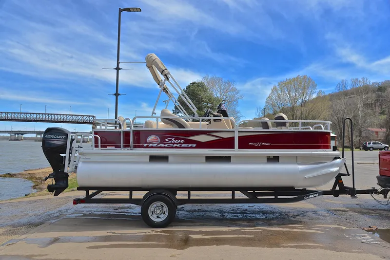 Slide: The Image of 2018 Sun Tracker Bass Buggy 18 DLX pontoon boat on trailer by a river. - 15