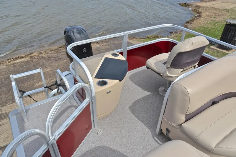 Slide: The Image of 2018 Sun Tracker Bass Buggy 18 DLX pontoon boat interior with seating and helm near water. - 24