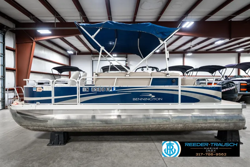 Slide: The Image of 2011 Bennington 20 SFI pontoon boat with blue canopy in indoor showroom. - 11