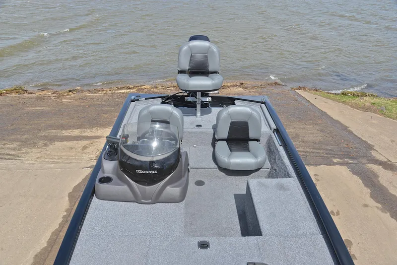 Slide: The Image of 2023 Bass Tracker Pro 170 boat with seating, docked by the water. - 23