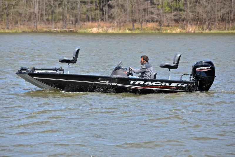 Slide: The Image of 2023 Bass Tracker Pro 170 boat cruising on a lake with a person steering. - 9
