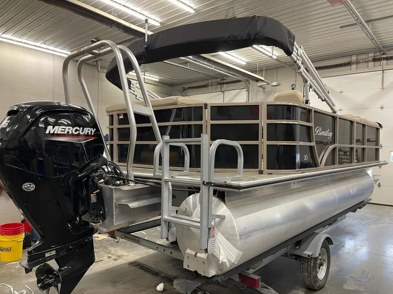 Slide: The Image of 2021 Bentley Pontoons Legacy 200 Cruise RE with Mercury outboard motor in a garage. - 5