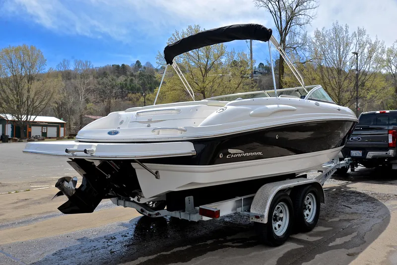 Slide: The Image of 2004 Chaparral 220 SSi boat on trailer, parked outdoors, with trees in the background. - 14