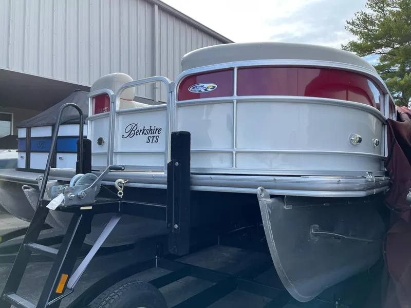Slide: The Image of 2016 Berkshire 233RFX STS pontoon boat on trailer, parked near a building. - 0