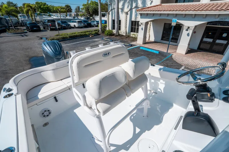 Slide: The Image of 2025 Sea Hunt Ultra 229 boat interior with helm and seating in a parking lot. - 17
