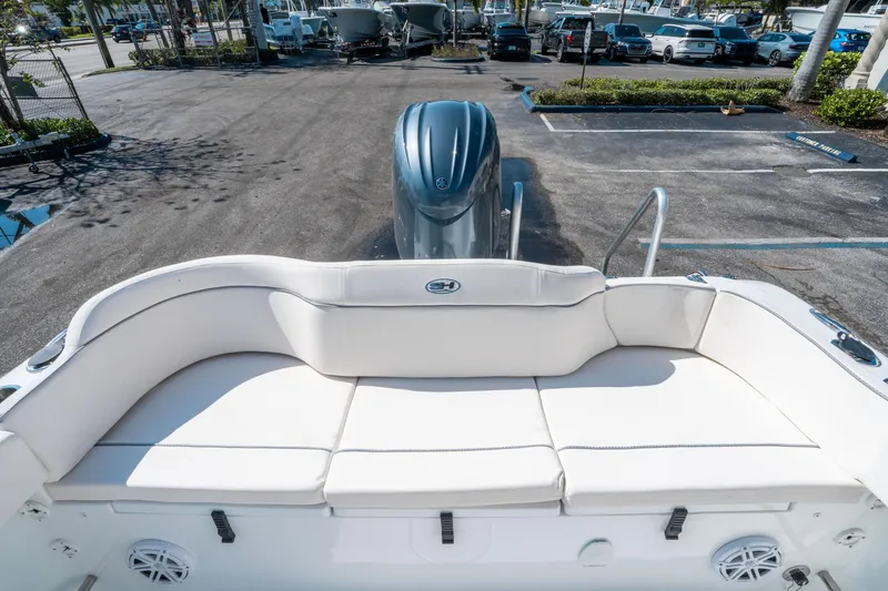 Slide: The Image of 2025 Sea Hunt Ultra 229 boat with white seating and outboard motor in a parking lot. - 10