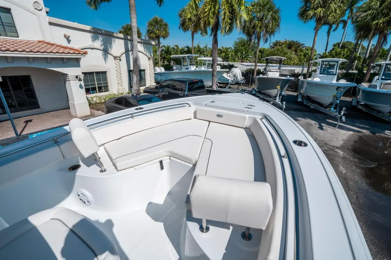 Slide: The Image of 2025 Sea Hunt Ultra 229 boat with white seating, parked outdoors near palm trees. - 21