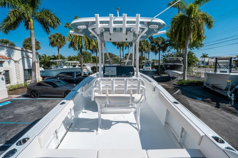Slide: The Image of 2025 Sea Hunt Ultra 229 boat in a sunny marina with palm trees. - 9