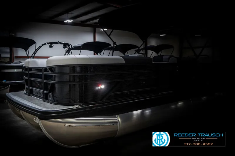 Slide: The Image of 2025 Bennington 21 SL pontoon boat in a dimly lit showroom. - 4