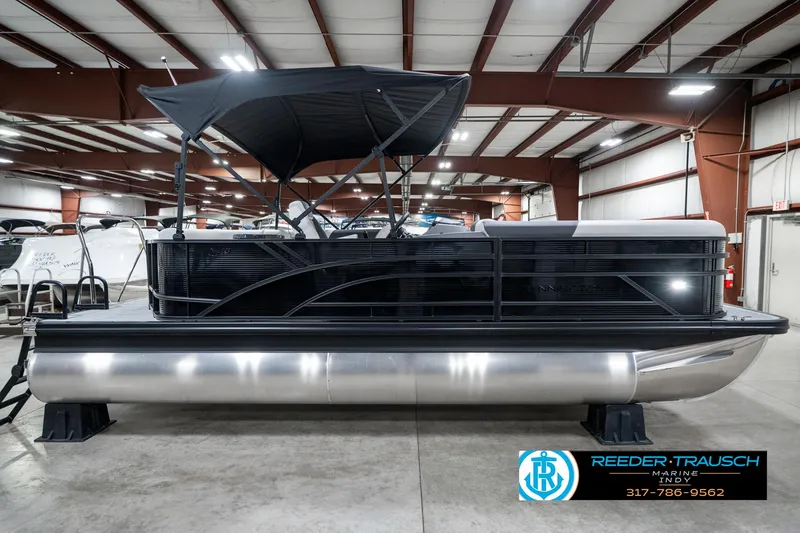 Slide: The Image of 2025 Bennington 21 SL pontoon boat in showroom, black canopy, sleek design. - 7