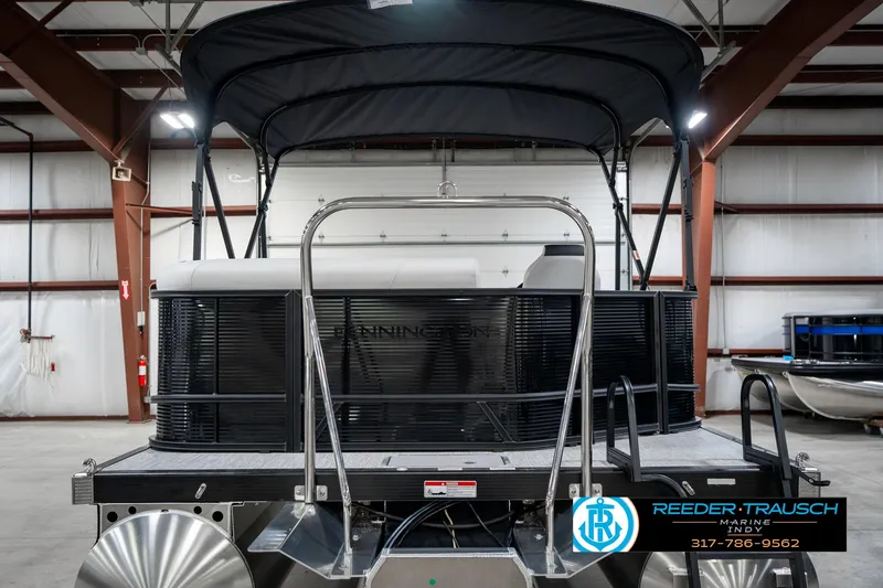 Slide: The Image of 2025 Bennington 21 SL pontoon boat in a warehouse, featuring a sleek black canopy. - 9