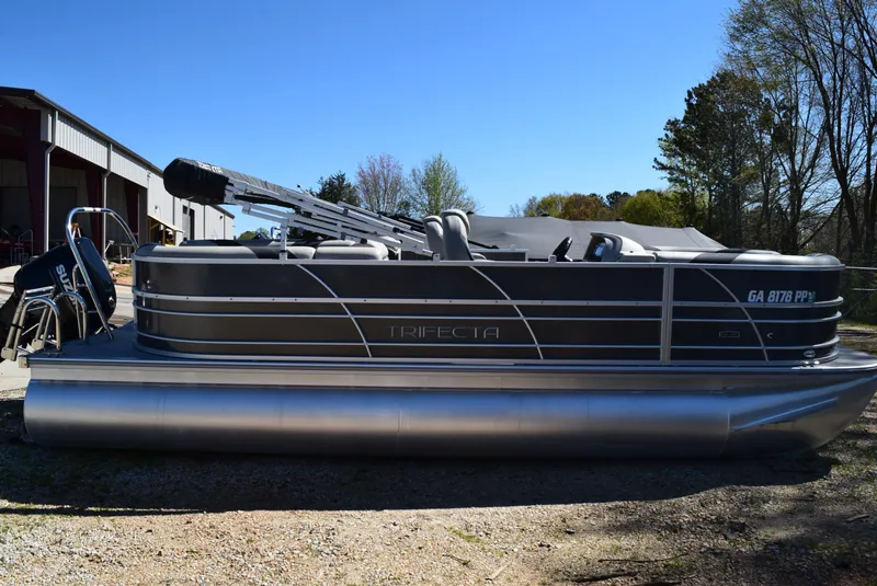 Slide: The Image of 2023 Trifecta 22RF LE 2.75 pontoon boat parked outdoors on a sunny day. - 1