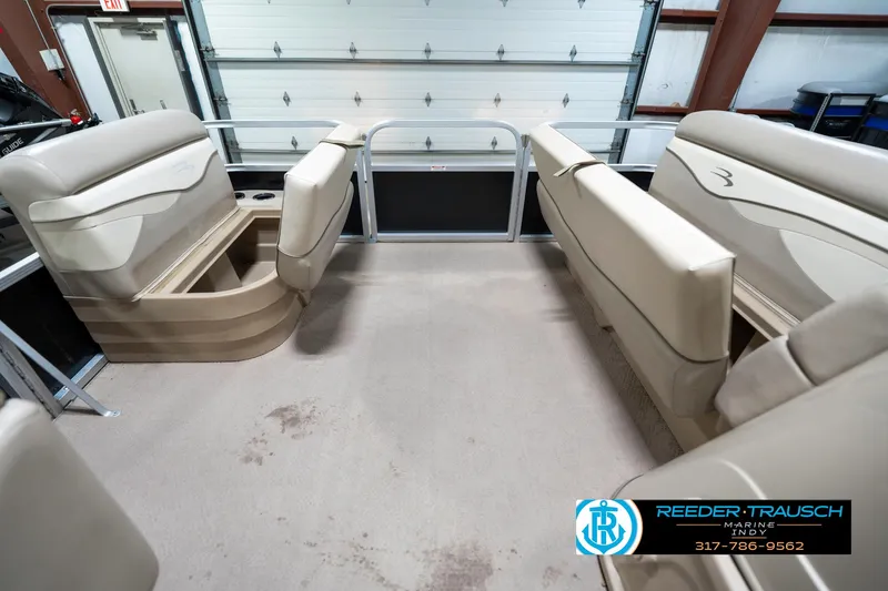 Slide: The Image of 2011 Bennington 17 Sli pontoon boat interior with beige seating in a garage. - 20