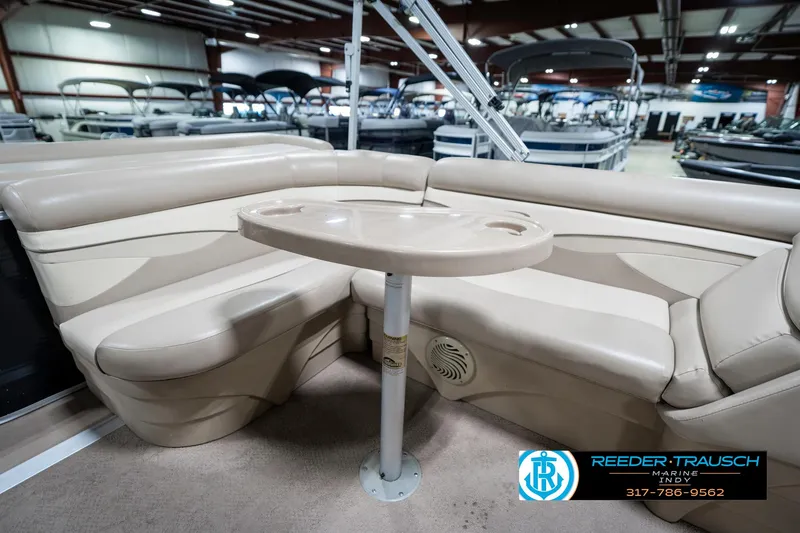 Slide: The Image of 2011 Bennington 17 Sli pontoon boat interior with beige seating and table in showroom. - 23