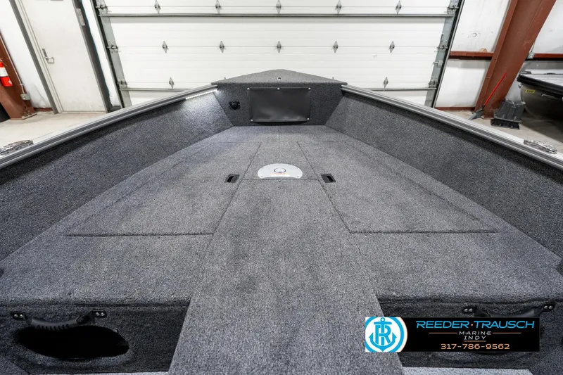 Slide: The Image of 2025 Lund 1775 Pro Guide boat interior with gray carpeted deck in a garage. - 16