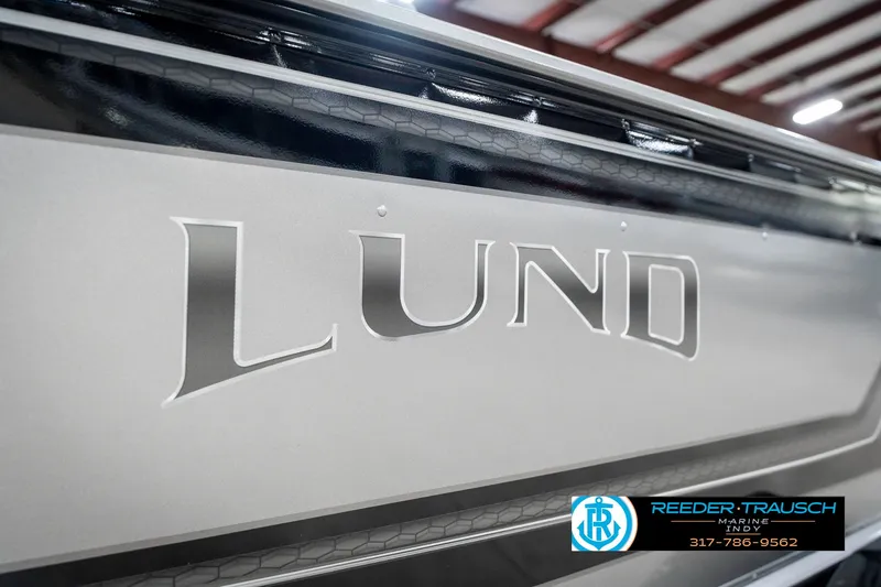Slide: The Image of 2025 Lund 1775 Pro Guide boat, close-up of logo, in a showroom setting. - 46