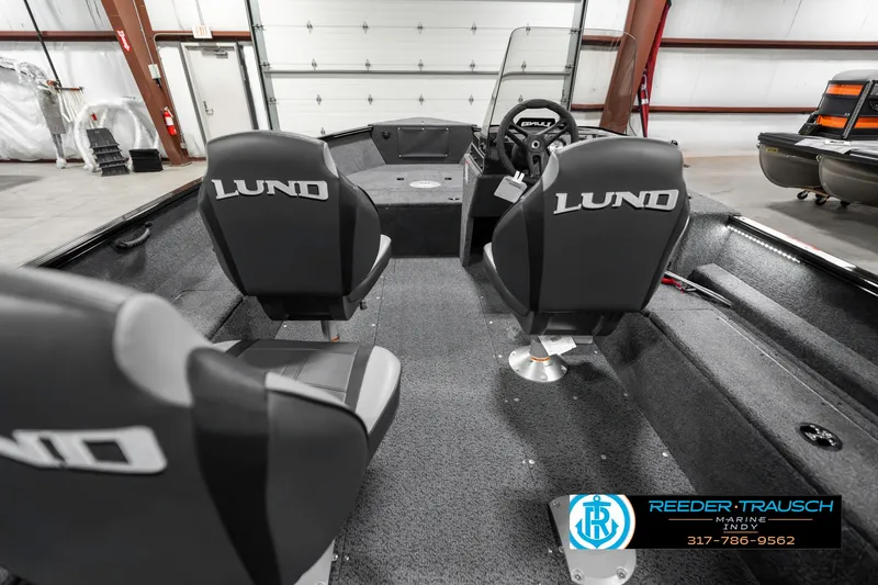 Slide: The Image of 2025 Lund 1650 Rebel XL SS boat interior with seating and steering console in a showroom. - 14