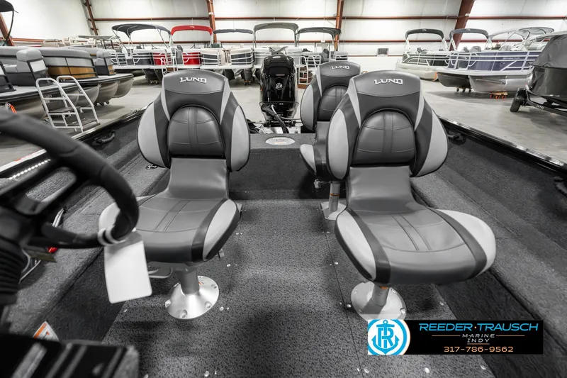 Slide: The Image of 2025 Lund 1650 Rebel XL SS boat interior with four gray seats in a showroom. - 18