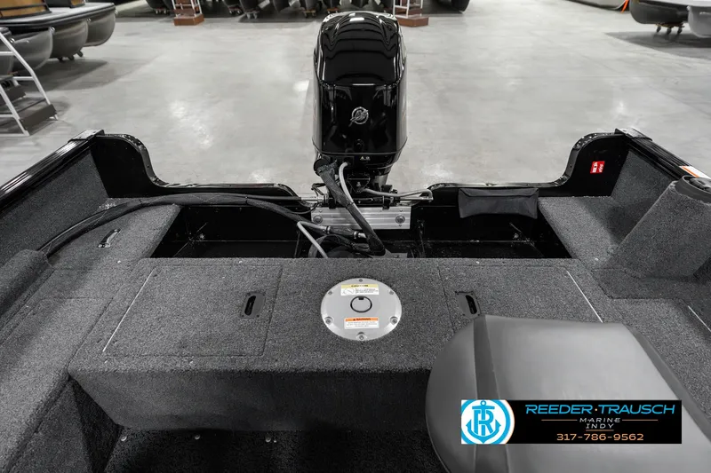 Slide: The Image of 2025 Lund 1650 Rebel XL SS boat interior with motor, gray carpet, and storage compartments. - 19