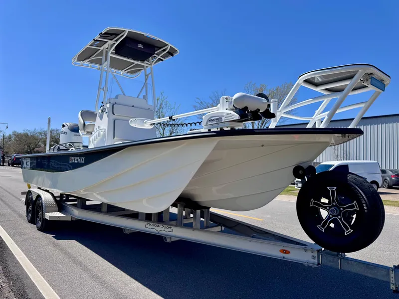 Slide: The Image of 2024 Shallow Sport 25 X3 boat on trailer, parked on street under clear blue sky. - 5