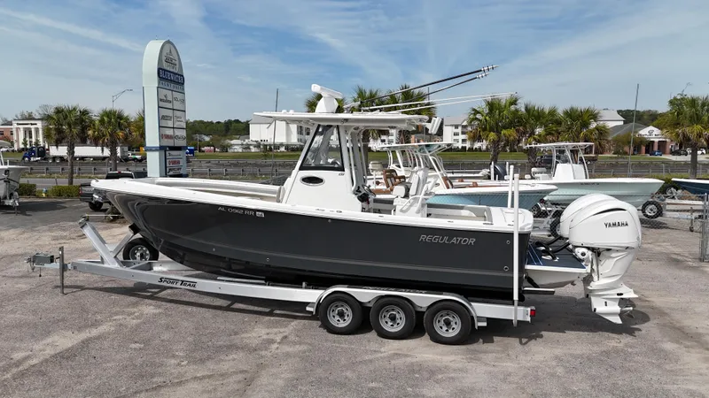 Slide: The Image of 2023 Regulator 28 boat on trailer, parked outdoors with palm trees in the background. - 0