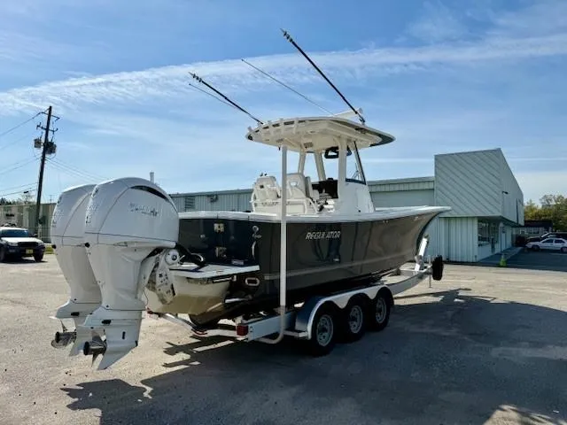 Slide: The Image of 2023 Regulator 28 boat on trailer with dual outboard engines, parked outdoors. - 4