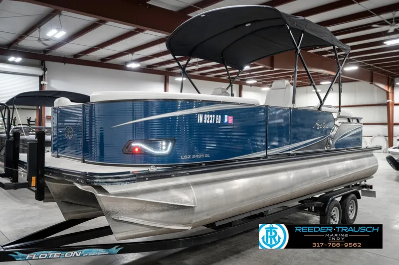 Slide: The Image of 2020 Avalon 2485 pontoon boat with blue exterior on a trailer in a warehouse. - 3