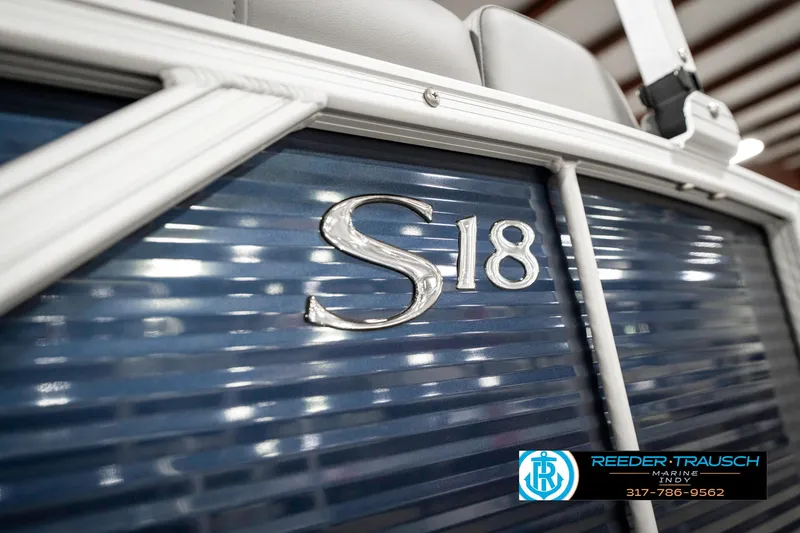 Slide: The Image of 2025 Bennington 18 SLJ boat with S18 emblem, blue paneling, and Reeder-Trausch Marine logo. - 49