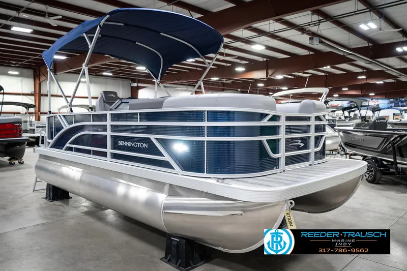 Slide: The Image of 2025 Bennington 18 SLJ pontoon boat with blue canopy in showroom. - 6