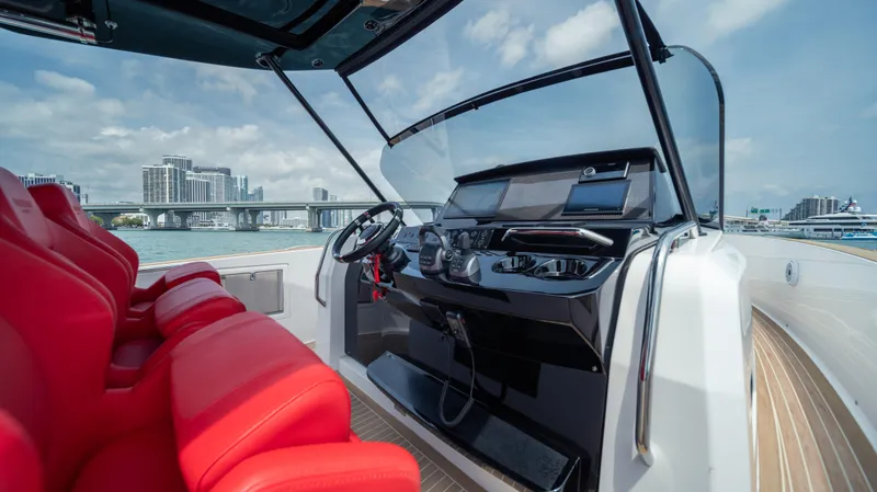 Slide: The Image of 2023 Pardo Yachts 38 helm with red seats, modern controls, and cityscape background. - 25